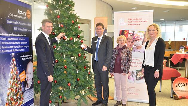 Stefan M&uuml;ller und Roland Stopfer befestigen ihre W&uuml;nsche am Baum. Der Erl&ouml;s geht diesmal an die Elterninitiative krebskranker Kinder aus Erlangen, vertreten durch Christine Tr&auml;g und Christine Habermann (von links)  Foto: Bernnhard Panzer