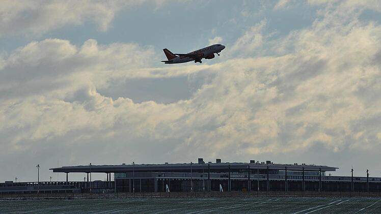 in Flugzeug fliegt am 11.01.2013 in Berlin über den Terminal des Großflughafen BER in Schönefeld. Nach der erneuten Absage des Eröffnungstermins ist unklar, wann die Fluglinien vom BER abheben werden. Foto: Paul Zinken/dp