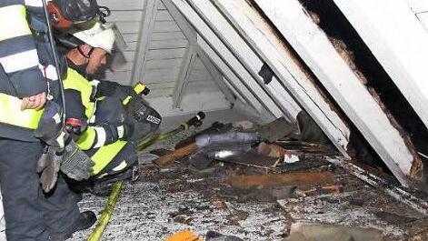 Mit einer Wärmebildkamera suchen Feuerwehr-Einsatzkräfte nach Glutnestern im Dachboden. Fotos: Michael Stelzner