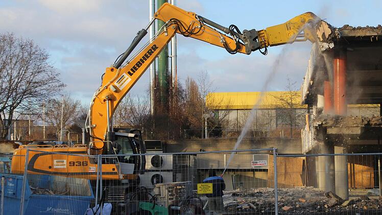 Mit enormen Kräften beißt die Beton-Zange des Baggers Stücke aus der Fassade. Gegen die Staubentwicklung wird Wasser gesprüht. Foto: Sabnine Weinbeer