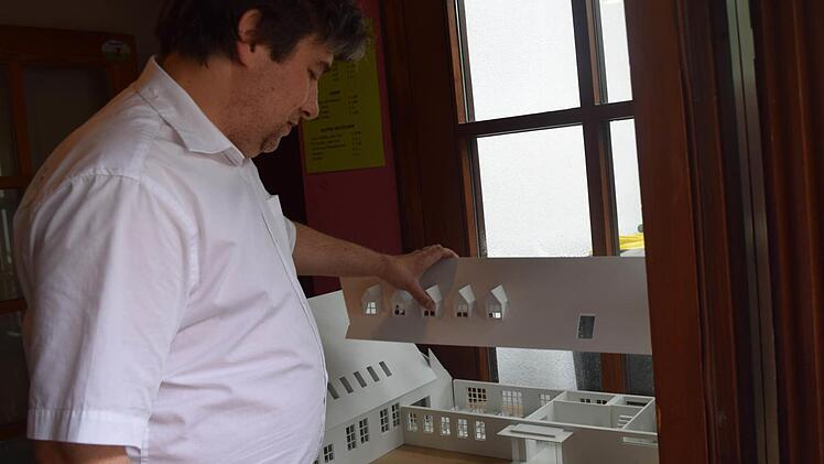Pfarrer Jörg Herrmann anhand eines Modells, was an der Kirche alles geändert werden soll. Foto: Daniela Pondelicek