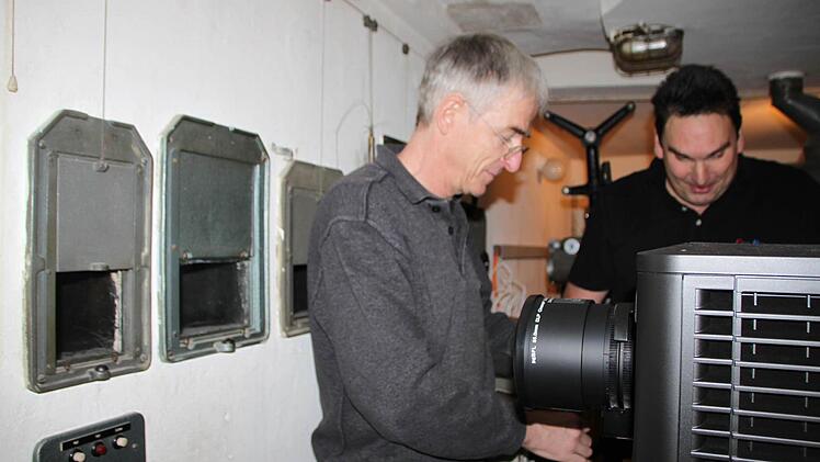 Rainer Mensing und Alexander Appel installieren den neuen Projektor. Die Linse wirft die Bilder durch eine der drei Öffnungen in der Wand. Foto: Ulrike Müller