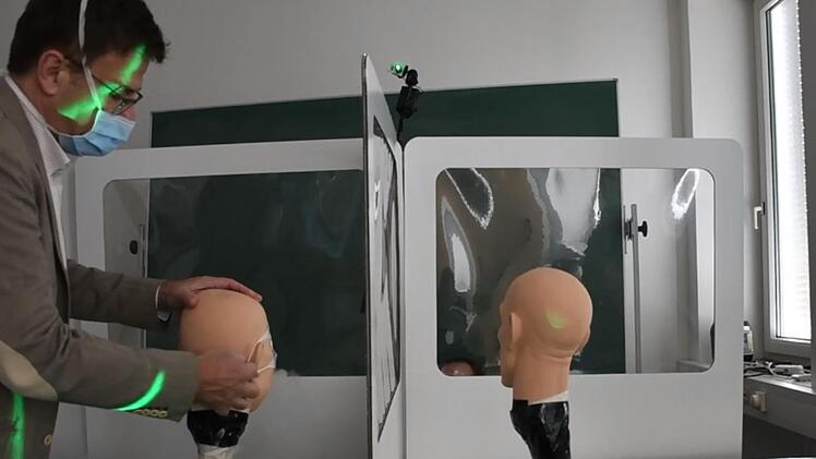 Peter Dahlem entfernt die Maske: In den Versuchen kam heraus, dass der Schutz durch Trennwände unabhängig vom Mund-Nasenschutz besteht. Foto: Hochschule Coburg