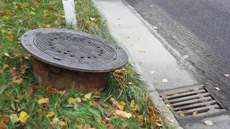 Die Kanaldeckel werden während der Fräsarbeiten aus der Straße gebracht und am Rand gelagert. Wegen der Gullyeinläufe wird eine schmale Fräse eingesetzt.  Foto: Friedwald Schedel
