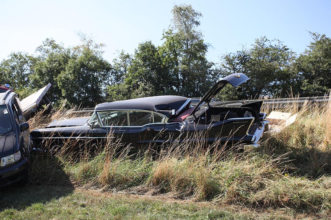 Mit Cadillac beladener Auto-Anhaenger kommt von der Fahrbahn ab