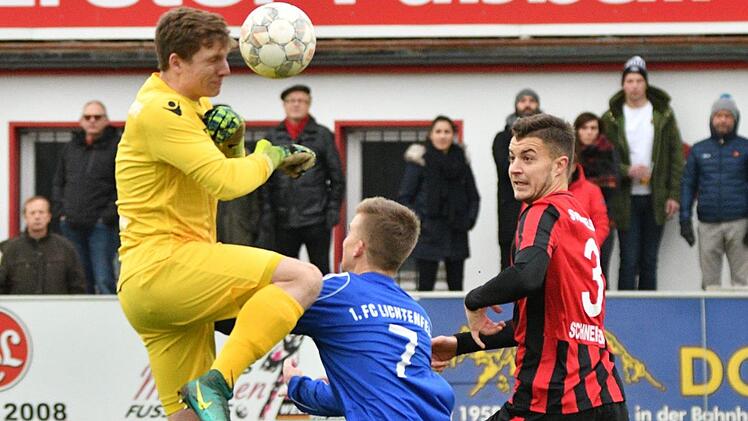 Rettung an der Strafraumgrenze: Der Memmelsdorfer Torwart Thomas Schuberth (links) kl&auml;rt per Kopfball vor dem Lichtenfelser Christopher Schaller (Mitte).  Fotos: Gunther Czepera