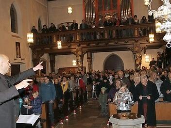 Dirigent Ingo Behrens animiert die Konzertbesucher, mitzusingen. Foto: Mathias Erlwein