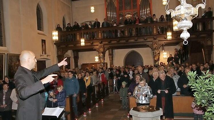 Dirigent Ingo Behrens animiert die Konzertbesucher, mitzusingen. Foto: Mathias Erlwein