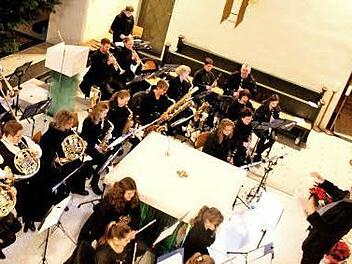 Kinder zünden die Kerzen in den Schiffchen an (Bild oben). Dirigent Jürgen Schatz und die Musiker erfreuten die Konzertbesucher in Adelsdorf. Fotos: Johanna Blum