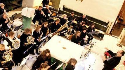 Kinder zünden die Kerzen in den Schiffchen an (Bild oben). Dirigent Jürgen Schatz und die Musiker erfreuten die Konzertbesucher in Adelsdorf. Fotos: Johanna Blum