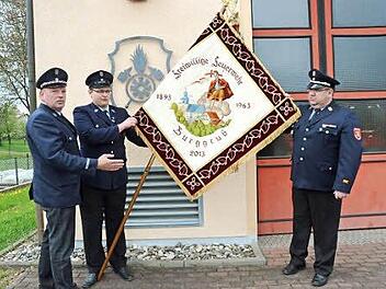 Erster Vorsitzender Manfred Drechsler, Fähnrich Dirk Kreul und Erster Kommandant Dirk Raupach zeigen die restaurierte Fahne.  Foto: Hofmann