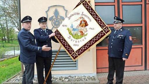 Erster Vorsitzender Manfred Drechsler, Fähnrich Dirk Kreul und Erster Kommandant Dirk Raupach zeigen die restaurierte Fahne.  Foto: Hofmann