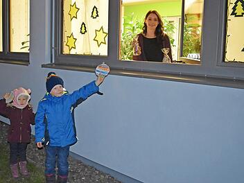 Annika und Oskar geben am Adventsfenster des Rathauses ihre bunt bemalten Weihnachts-Wunsch-Kugeln ab, während Engel Bianca (am Fenster) schon die Geschenke bereithält.  Foto: che