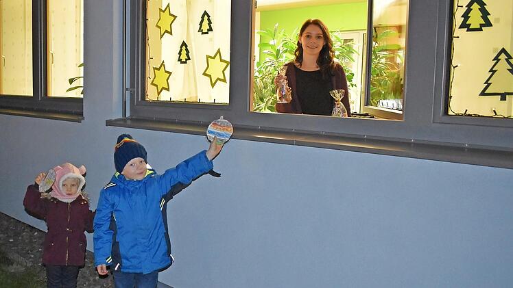 Annika und Oskar geben am Adventsfenster des Rathauses ihre bunt bemalten Weihnachts-Wunsch-Kugeln ab, während Engel Bianca (am Fenster) schon die Geschenke bereithält.  Foto: che