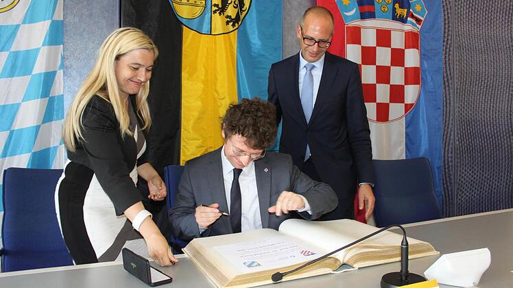 Eintrag ins Goldene Buch des Landkreises, von links Ministerin Melanie Huml, Minister Predrag Šustar und Landrat Christian Meißner.