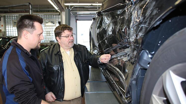 Kfz-Meister Alexander Müller und Polizist Joachim Reininger begutachten einen Schaden: Wenn es sich hier um eine Unfallflucht gehandelt hätte, würde die eingeklemmte Glasscherbe vom gegnerischen Fahrzeug Rückschlüsse auf die Fahrzeugmarke zulassen. Foto: Ralf Ruppert