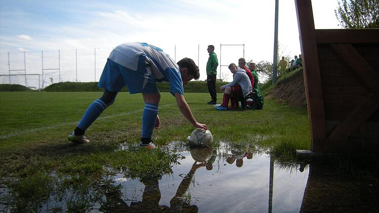 Spiegelbild: Nicolas Wrobel von der SG Oberleichtersbach holt den Ball aus der Pfütze vor der Trainerbank. Gegen die U15 der SG Oehrberg verlor Wrobels Team mit 0:2. Foto: ssp