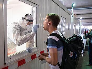 Immer mehr Menschen kehren aus dem Urlaub zurück. Ein Mitarbeiter der Johanniter-Unfall-Hilfe nimmt einen Abstrich im Corona-Testzentrum am Flughafen Hannover-Langenhagen von einem Reiserückkehrer. Foto: Moritz Frankenberg/dpa