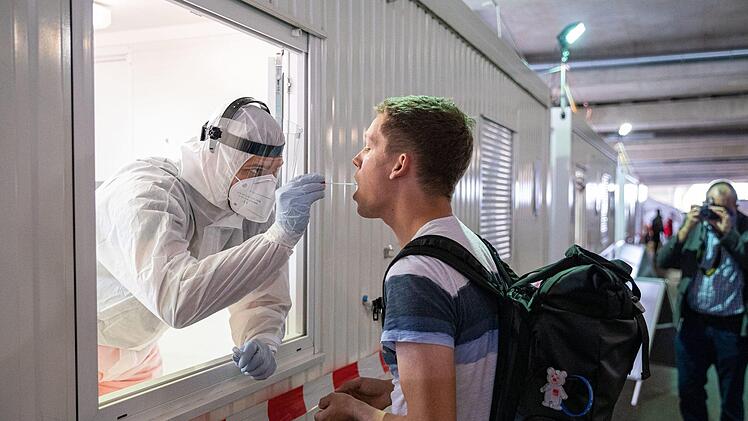 Immer mehr Menschen kehren aus dem Urlaub zurück. Ein Mitarbeiter der Johanniter-Unfall-Hilfe nimmt einen Abstrich im Corona-Testzentrum am Flughafen Hannover-Langenhagen von einem Reiserückkehrer. Foto: Moritz Frankenberg/dpa
