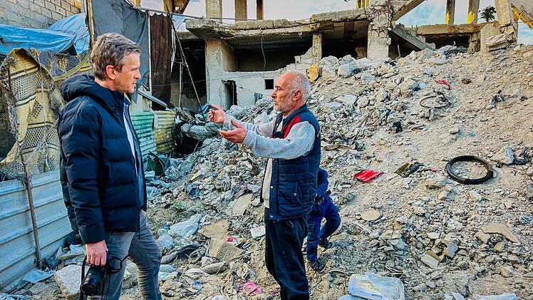 Baba Mahhouz (rechts) erzählt Markus Lanz vor seinem zerbombten Haus in Douma, Syrien, seine Geschichte.
