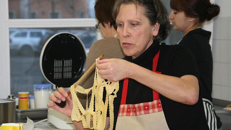 Gar nicht so einfach: Doris Seelkopf fädelt die zusammenhängenden Teigstreifen über den Stiel des Kochlöffels. Foto: Daniela Röllinger