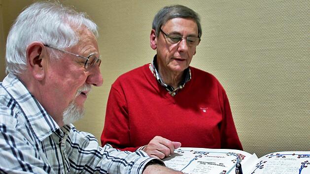 Die neuen Ehrenmitglieder Reinhold Sch&auml;dlich und Peter J&uuml;ngst (dahinter) tragen sich in das von ihnen mitgestaltete "Goldene Buch" des Heimatvereins ein. Foto: Werner Vogel