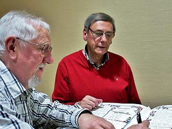 Die neuen Ehrenmitglieder Reinhold Schädlich und Peter Jüngst (dahinter) tragen sich in das von ihnen mitgestaltete "Goldene Buch" des Heimatvereins ein. Foto: Werner Vogel