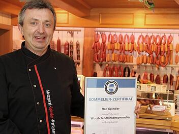 Ralf Spindler mit Urkunde und einer Auswahl von Schinken in seinem Laden. Foto: Franz Galster