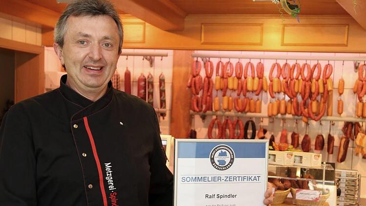 Ralf Spindler mit Urkunde und einer Auswahl von Schinken in seinem Laden. Foto: Franz Galster