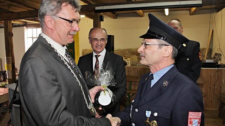 Karl-Ludwig Müller (rechts) erhält von seinem "Chef", Bürgermeister Helmut Dietz, ein Präsent, nachdem zuvor Landrat Wilhelm Schneider (Mitte) an den Feuerwehrmann für 40 Jahre Dienstzeit das Ehrenzeichen verliehen hatte.   Foto: Helmut Will