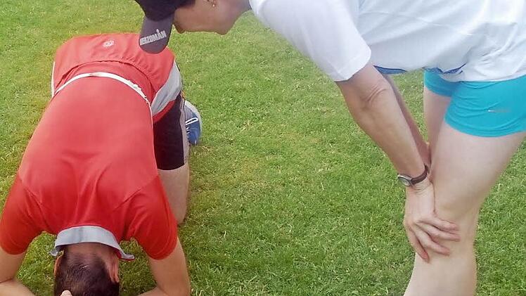 Totale Erschöpfung: Ein Triathlet muss nach getaner Arbeit erstmal wieder zu Luft kommen, eine Helferin sieht nach dem Rechten.