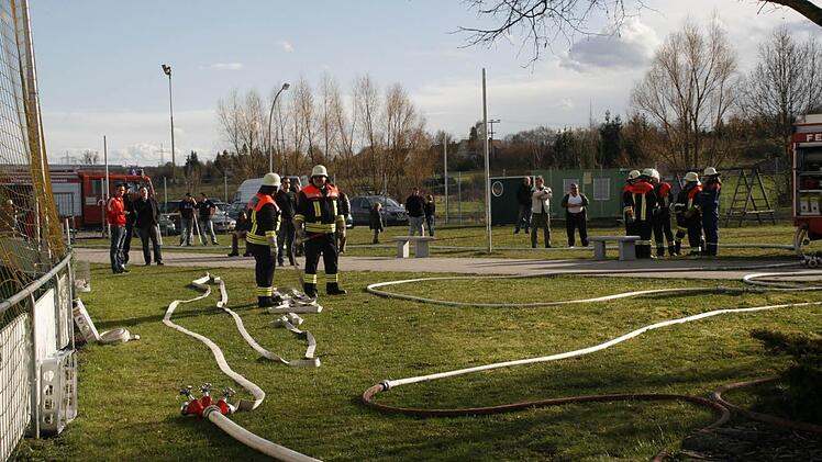 Feuerwehrschläuche, Feuerwehrleute und entsetzte Mitglieder auf dem Sportgelände. Foto: G. Bauer
