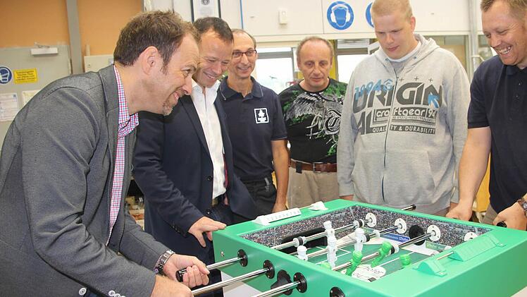 Purer Spaß garantiert: Volker Hartmann (links), Geschäftsführer der Hofer eds GmbH, hat den Ein-Mann-Kicker als Spielgerät für seine Entwicklungsmannschaft in Würzburg bestellt. In der Werkstatt der Barmherzigen Brüder wurde es genau nach Wünsch individuell angefertigt. Beim Abholen war ein Probe-Match Ehrensache. Hartmann lieferte sich mit Rainer, der in der Endmontage arbeitet, ein spannendes Duell.  Foto: Diana FuchsPurer Spaß garantiert: Volker Hartmann (links), Geschäftsführer der Hofer ...