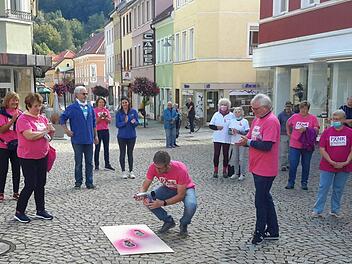 In die Hocke ging Bürgermeister Jochen Vogel (Bildmitte), um farbige Fußabdrücke auf das Straßenpflaster zu sprühen. Mit der symbolischen Geste eröffnete er eine Spenden- und Aktionswoche, die in diesem Jahr den Pinklauf ersetzt. Foto: Rolf Pralle