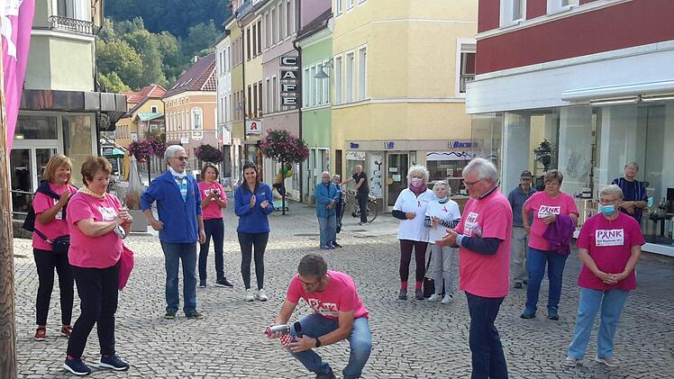 In die Hocke ging Bürgermeister Jochen Vogel (Bildmitte), um farbige Fußabdrücke auf das Straßenpflaster zu sprühen. Mit der symbolischen Geste eröffnete er eine Spenden- und Aktionswoche, die in diesem Jahr den Pinklauf ersetzt. Foto: Rolf Pralle