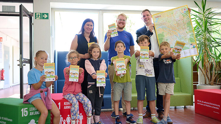 Schulleiterin Jasmin Kremer, Maxi Manlig vom Stadtjugendring und B&uuml;rgermeister Jonas Gl&uuml;senkamp (v.l.) zeigen gemeinsam mit Kindern der Hainschule den &uuml;berarbeiteten Kinderstadtplan.