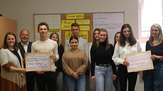 Lehrerin Lisa Menstell (von links), Schulleiter Markus Arneth, die Sch&uuml;lerinnen und Sch&uuml;ler des Seminars sowie Jutta Ort von der  Caritas Bad Kissingen  (rechts) bei der &Uuml;bergabe des symbolischen Schecks.