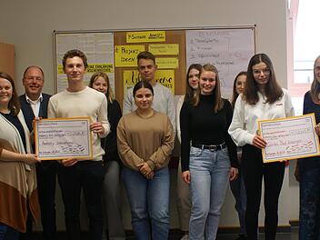 Lehrerin Lisa Menstell (von links), Schulleiter Markus Arneth, die Schülerinnen und Schüler des Seminars sowie Jutta Ort von der  Caritas Bad Kissingen  (rechts) bei der Übergabe des symbolischen Schecks.