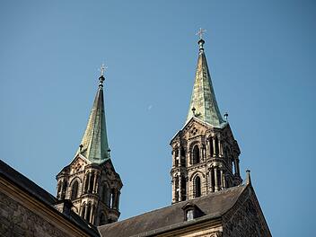 Zwei gotische Kircht&uuml;rme mit gr&uuml;nlichen D&auml;chern erheben sich vor einem klaren blauen Himmel, der Mond ist im Hintergrund sichtbar. M&ouml;glicher Bezug zu geplanten Besichtigungsgeb&uuml;hren.