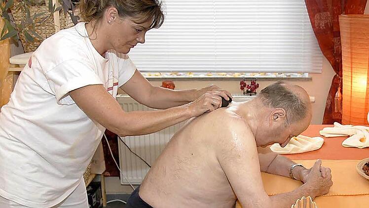 Massagen mit warmen Steinen lösen Blockaden: Heinz Dörfler leidet an Rückenbeschwerden und ist dankbar für Judith Wocheles Wellness-Einheiten. Der eigens für das Projekt eingerichtete Behandlungsraum im Wohnstift sorgt mit Kerzenschein und warmen Farben dafür, dass die Atmosphäre stimmt und alle Sinne anspricht. Fotos: Dagmar Besand