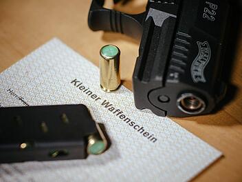 Ein kleiner Waffenschein liegt zwischen einer Schreckschuss-Pistole "Walther P22", einem Magazin und einer Knallpatrone. Sind Schreckschusswaffen in der Silvesternacht erlaubt? Diese Regeln gelten für das Tragen und Abfeuern