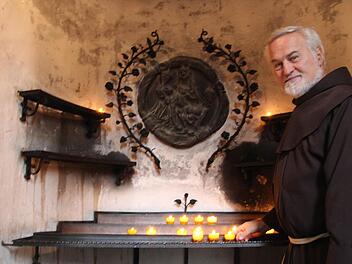 Pater Richard zündet eine Kerze an. Die Wallfahrtskirche Maria im Sand liegt ihm sehr am Herzen. Foto: Dieter