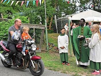 Pfarrer Solomon segnete nach dem Gottesdienst zu Beginn des Kellerfestes des Radfahr- und Motorsportclubs "Viktoria 1912" Dampfach die anwesenden Motorrad- und Fahrradfahrer, darunter Martin Scheppan mit seinem Sohn Levi auf seiner Suzuki .  Foto: Ulrike Langer