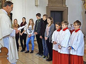 Moritz Hetzel, Johannes Müller und Klara Klostermann (von rechts) wurden von Pfarrer Georg Birkel in ihr Amt als Ministranten eingeführt. Mit auf dem Bild die Jugendlichen, die sie auf diesen Tag vorbereitet haben.  Foto: Thomas Hümmer