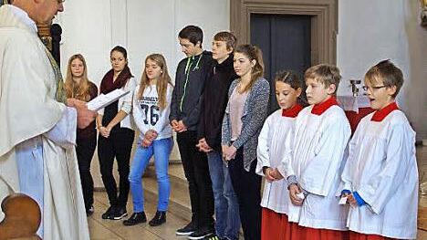 Moritz Hetzel, Johannes Müller und Klara Klostermann (von rechts) wurden von Pfarrer Georg Birkel in ihr Amt als Ministranten eingeführt. Mit auf dem Bild die Jugendlichen, die sie auf diesen Tag vorbereitet haben.  Foto: Thomas Hümmer
