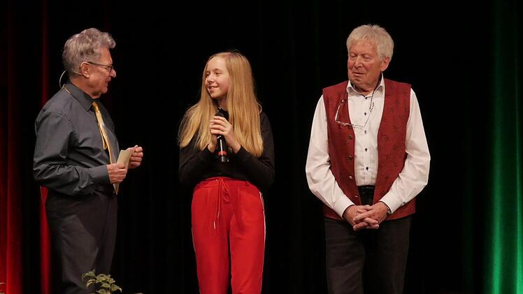 Moderator Wolfgang Doischer (links) dankt Dirigent Manfred Deinhart (rechts) und seiner Enkelin Annika für ihre musikalischen Beiträge. Foto: Manja von Nida