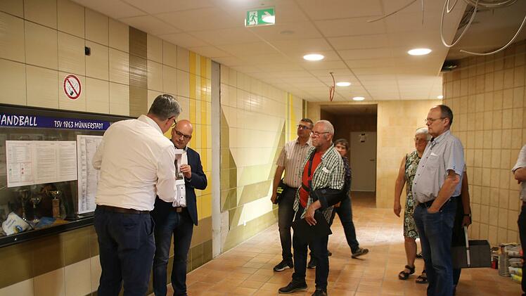 Bauleiter Mustafa Zecic (links) und Bürgermeister Michael Kastl zeigen, wie die Wand im Eingangsbereich aussehen könnte. Die Fliesen sollen eigentlich bleiben, aber es gibt Stellen, wo etwas Neues hin muss. Foto: Thomas Malz