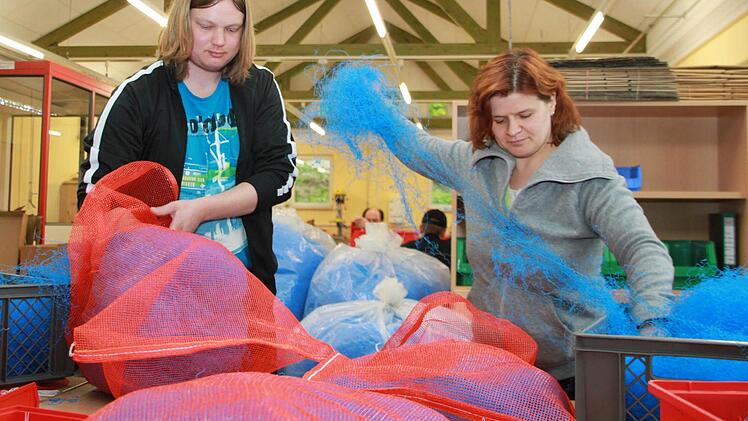 Heiko und seine Kollegin Tanja sind ein eingespieltes Team. Das Befüllen der Plastiksäcke, die später einmal als Filter in Kleinkläranlagen zum Einsatz kommen, geht ihnen leicht von der Hand. Foto: Katrin Geyer