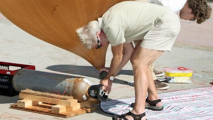 Otto Lotz bläst nochmals Helium in den Ballon, Patrick kontrolliert die Flugbox.