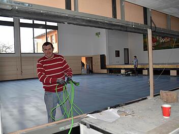 Ein Blick von der Küche in die Halle. Hier sind die Fußbodenbauer dabei, die Versiegelung des Hallenbodens vorzubereiten. Die Durchreichen im Vordergrund werden mit Rolltoren geschlossen, die auf der Hallenseite mit Prallschutz versehen sind. Foto: Kathrin Kupka-Hahn